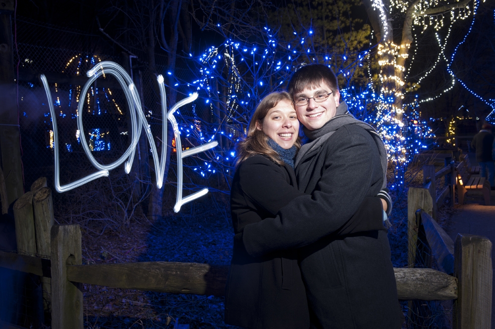 Engagement Photography - long exposure hugging in front of Christmas lights