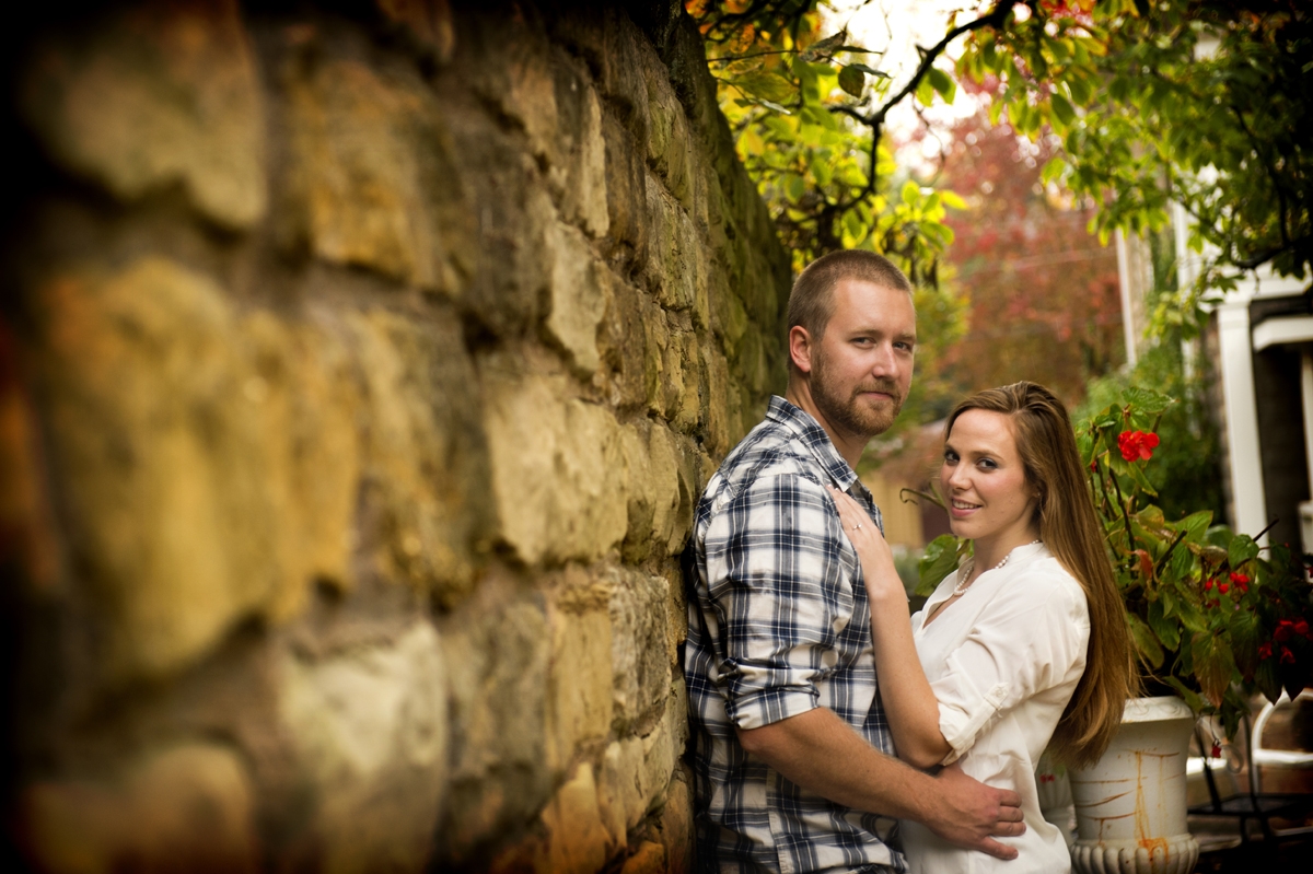 Engagement Photography - Couple hugging against stone wall in autumn