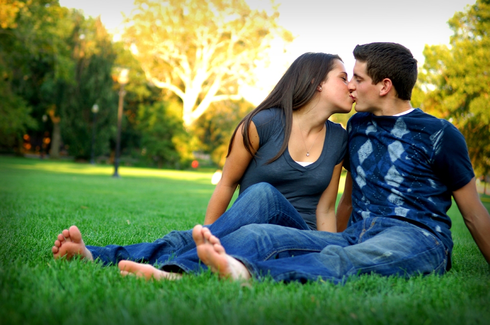 Engagement Photography - Outdoor couple kissing while relaxing in the grass
