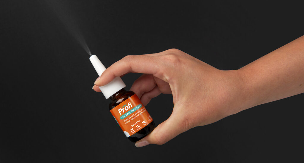Product photo showing spray with hand model for Akita Biosciences Nasal Spray on black background