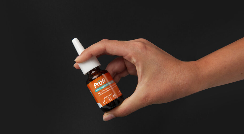 Product photo with hand model for Akita Biosciences Nasal Spray on black background